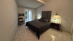 A bedroom with a bed, a chair, a desk, a lamp, and a window. - Village house nestled among ponds, scrubland, and a wild beach (La Palme)