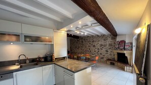 A modern kitchen with white cabinets, a built-in oven, and a stone wall in the background. - Village house nestled among ponds, scrubland, and a wild beach (La Palme)