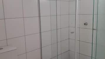 A corner shower enclosure with a glass door, a toilet, and a trash bin.