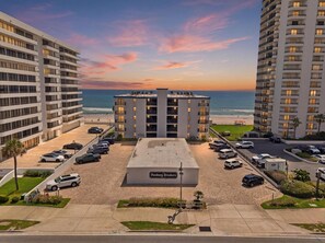 Ein Hochhaus-Hotel mit Parkplatz davor, Blick auf den Strand und einem Schild mit der Aufschrift 'Danbury Breakers'.