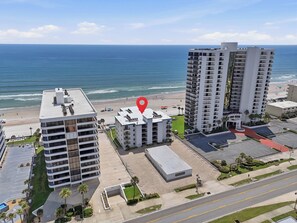 Ein Hochhaus-Hotel mit mehreren Etagen, einem Parkplatz und Blick auf den Strand.
