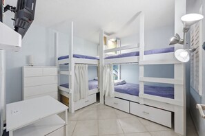 Ein Zimmer mit Etagenbetten, einem Schreibtisch und einer Lampe.