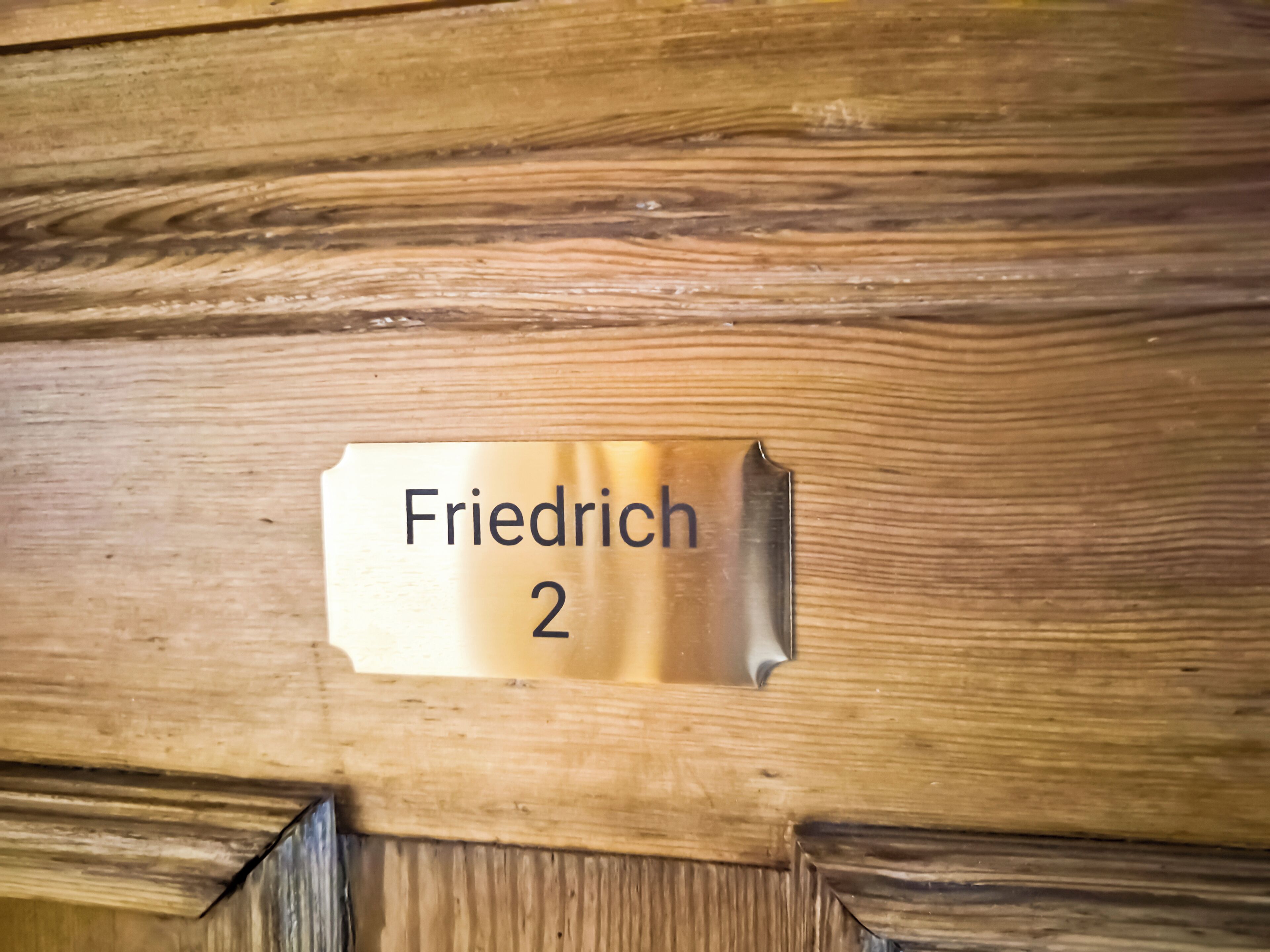 En dörr av trä med en metallplakett där det står ”Friedrich 2”.