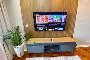 Un téléviseur à écran plat fixé à un mur en bois, diffusant différents contenus en streaming.