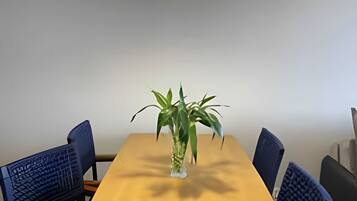 Spisebord med seks stole, en potteplante og en vævet pendellampe.