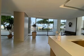 Un intérieur spacieux et moderne, doté de grandes fenêtres qui offrent une vue sur les arbres et un paysage lointain.