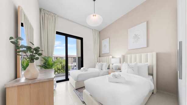 Habitación de hotel con dos camas, un espejo grande, una planta en maceta y vistas al exterior.