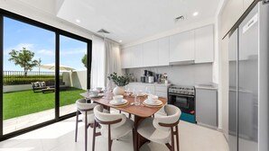 Una cocina moderna con comedor, ventanas amplias y vista a un césped verde.