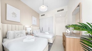 Habitación de hotel con dos camas, un aparador de madera, un espejo grande y obras de arte en las paredes.