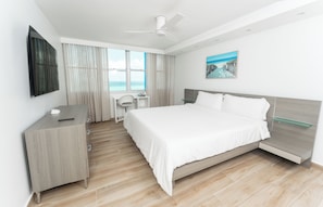 Ein modernes Hotelzimmer mit Bett, Schreibtisch, Stuhl und Blick auf den Ozean.