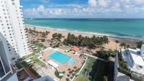 A high-rise hotel with a pool, beach view, and palm trees. - Casa Jenny 2BR2BA 2026 Remodeled (Carolina)