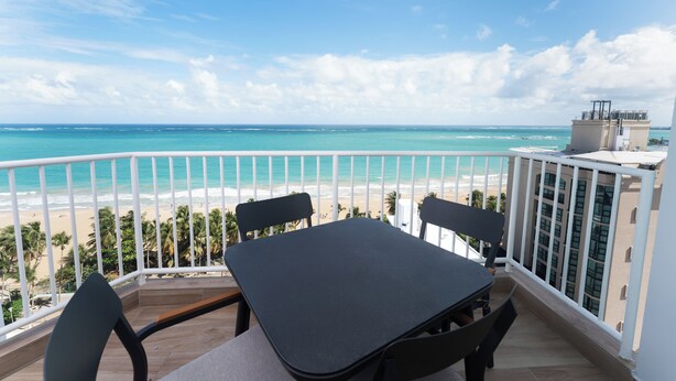 A balcony with a table and chairs overlooking a beach and ocean. - Casa Jenny 2BR2BA 2026 Remodeled (Carolina)
