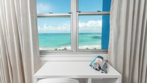 A room with a window overlooking a beach, a white desk, and a pair of shoes on the desk. - Casa Jenny 2BR2BA 2026 Remodeled (Carolina)