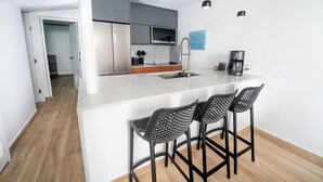 A modern kitchen with a white island, stainless steel appliances, and black bar stools. - Casa Jenny 2BR2BA 2026 Remodeled (Carolina)