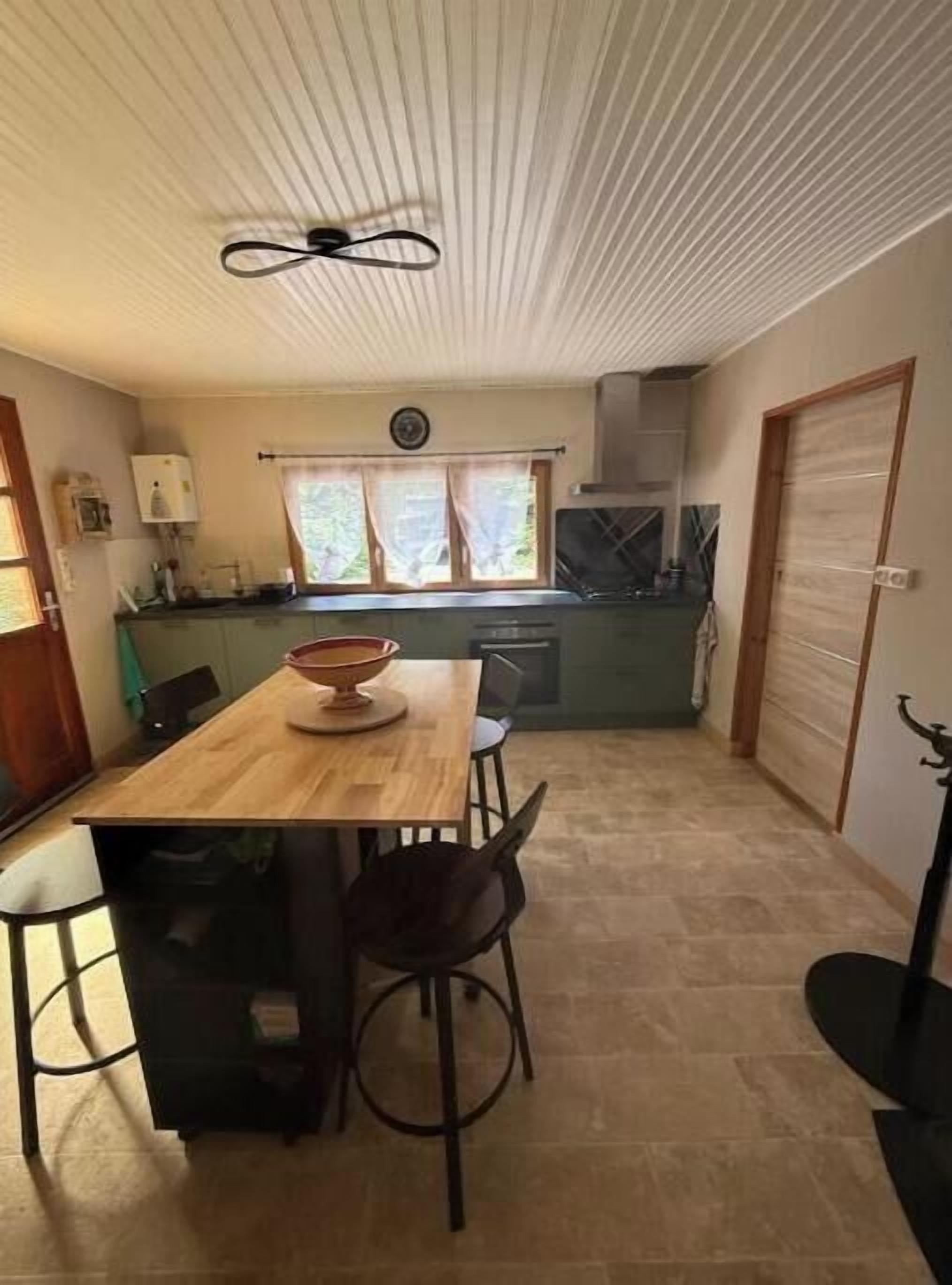 Een kleine keuken met een eettafel, stoelen en een plafondventilator.
