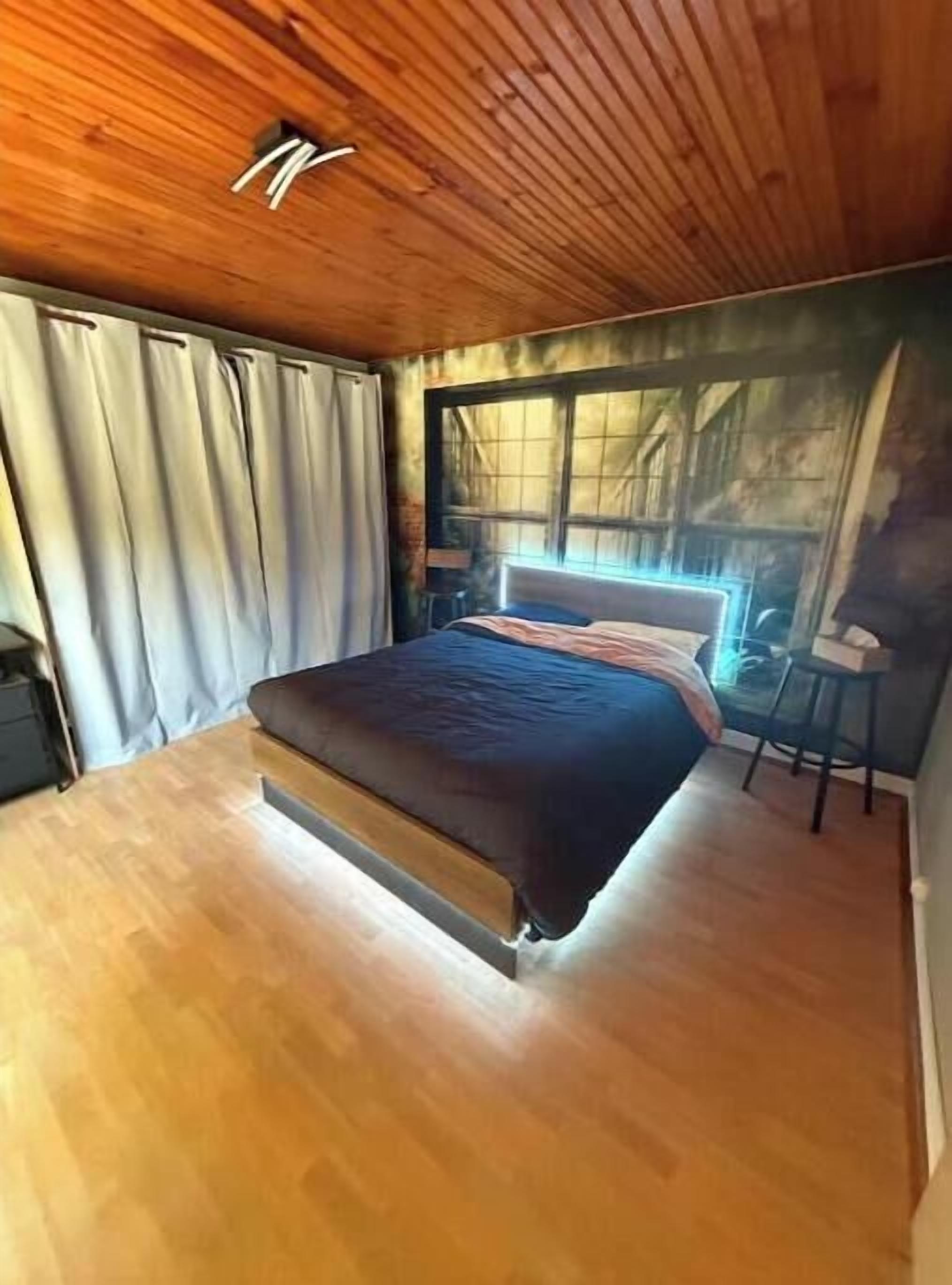 Ein Schlafzimmer mit Bett, Fenster und Holzboden.