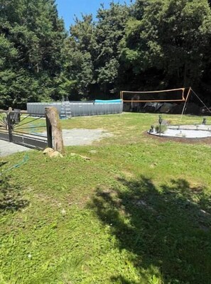An outdoor area with a grassy lawn, a metal fence, and trees in the background.