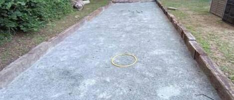 Un área exterior de concreto con un aro metálico en el centro, rodeada por un borde de madera.