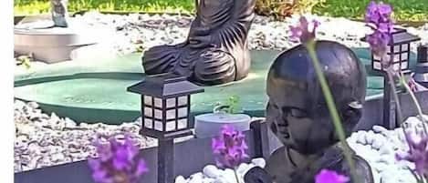 A garden with statues of seated figures and a lantern.