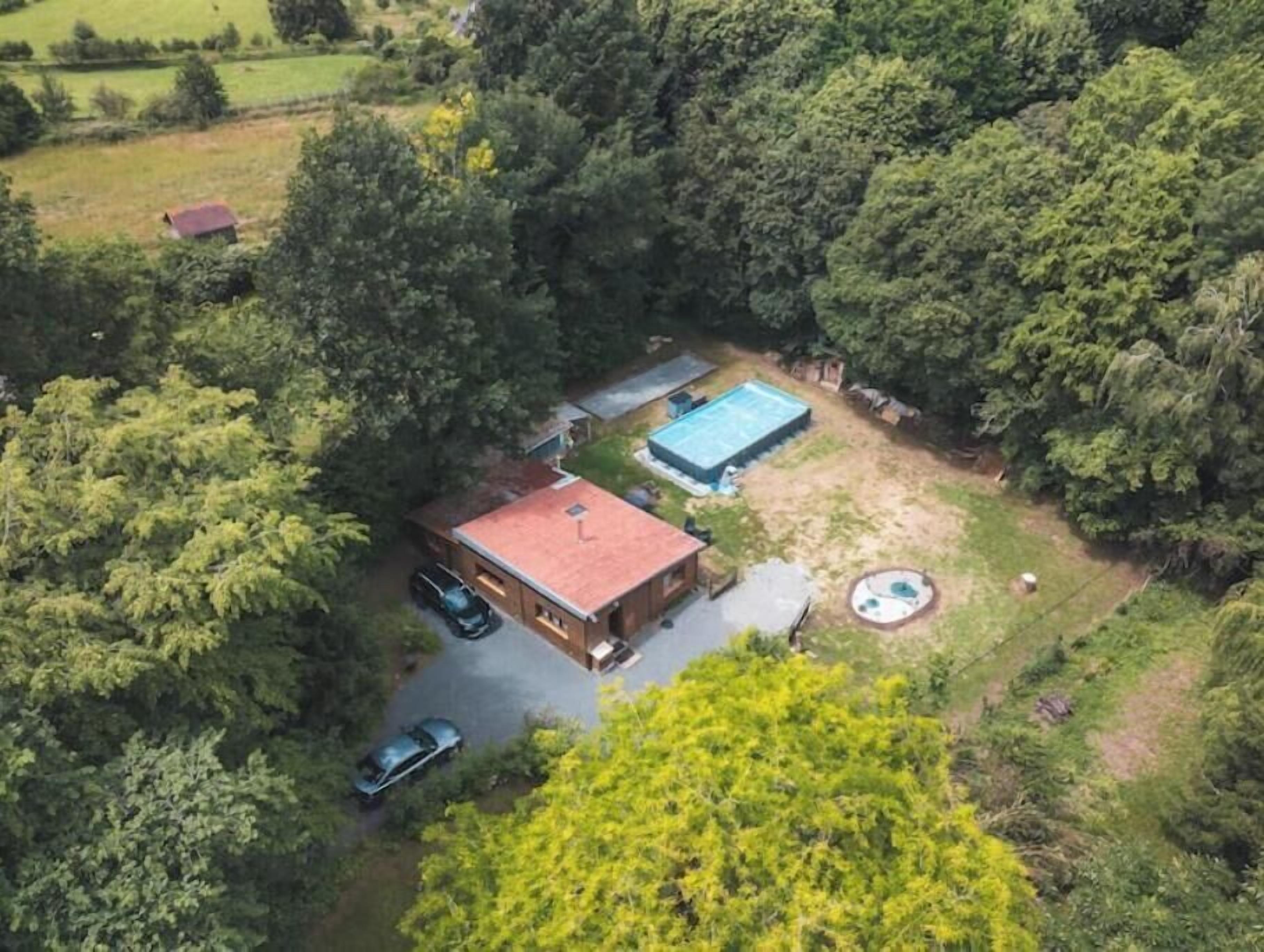 An aerial view of a property with a swimming pool, a red-roofed building, and a circular hot tub.