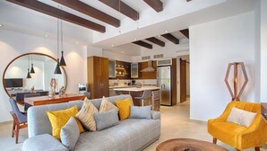 A modern living room with a sofa, coffee table, and a yellow armchair. There is a dining area with a table and chairs, and a kitchen in the background. - Awesome 2-bedroom condo with AC in vibrant Puerto Vallarta in Zona Romántica (Puerto Vallarta)