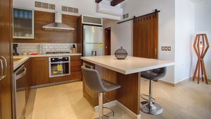 A modern kitchen with wooden cabinets, a stainless steel refrigerator, a gas stove, and a bar area with stools. - Awesome 2-bedroom condo with AC in vibrant Puerto Vallarta in Zona Romántica (Puerto Vallarta)