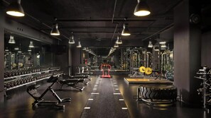 Une salle de sport équipée de matériel d’exercice, de supports pour les poids et de miroirs.