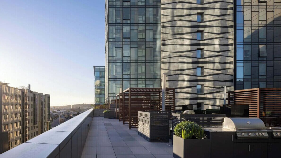 Une terrasse sur le toit offrant une vue sur le paysage urbain, les bâtiments modernes et un barbecue.