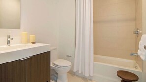 Et badeværelse med toilet, vask og badekar.