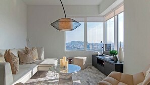A modern living room with a sofa, a coffee table, and a television. - Stylish 1BR Retreat with Modern Comforts at Nema (San Francisco)