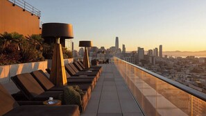 A rooftop terrace with lounge chairs and tables, offering a city skyline view. - Stylish 1BR Retreat with Modern Comforts at Nema (San Francisco)