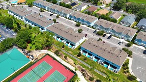 A residential area with multiple blue-toned houses, a parking lot, and a tennis court. - 5BR Private Pool Home Near Disney (Kissimmee)