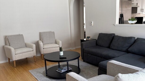 Ein modernes Wohnzimmer mit einer Couch, Sesseln, einem Couchtisch und einem Deckenventilator.