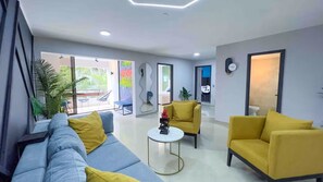 A modern living room with a sofa, armchairs, a coffee table, and a large window. - 4-bedroom Poblado Provenza walk to lleras (Medellín)