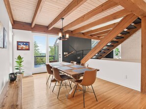 Un coin repas avec une table en bois, des chaises et un escalier.