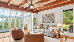 A spacious living room with a high ceiling, a ceiling fan, a large window, and a view of the outdoors. - Luxury Blue Ridge Retreat - Hot Tub - 15 Min to Early Mountain Vineyard (Stanardsville)