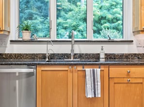 A kitchen with wooden cabinets, a granite countertop, a stainless steel sink, and a window with a view of greenery. - Luxury Blue Ridge Retreat - Hot Tub - 15 Min to Early Mountain Vineyard (Stanardsville)
