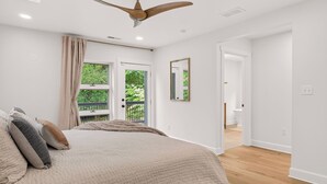 A bedroom with a bed, a ceiling fan, a window with curtains, and a door leading to another room. - Luxury Blue Ridge Retreat - Hot Tub - 15 Min to Early Mountain Vineyard (Stanardsville)