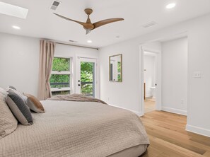 A bedroom with a bed, a ceiling fan, a window with curtains, and a door leading to another room. - Luxury Blue Ridge Retreat - Hot Tub - 15 Min to Early Mountain Vineyard (Stanardsville)
