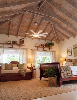 Un dormitorio acogedor con techo de madera, una cama, un sofá y un ventilador de techo.