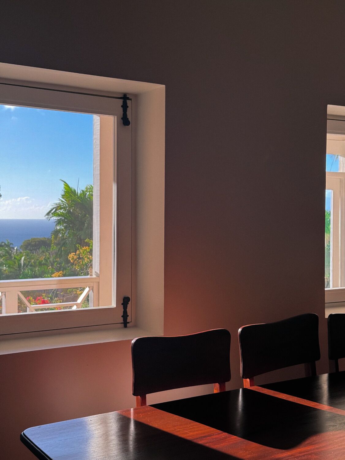 A room with a large window, a wooden table, and two chairs.
