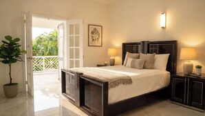 Quarto com cama, abajures, mesa de cabeceira, planta em vaso e vista para o exterior.