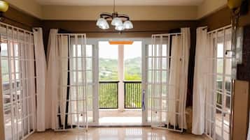 Ein Zimmer mit einer großen Glasdoor, die auf einen Balkon mit Blick auf Grünflächen führt.