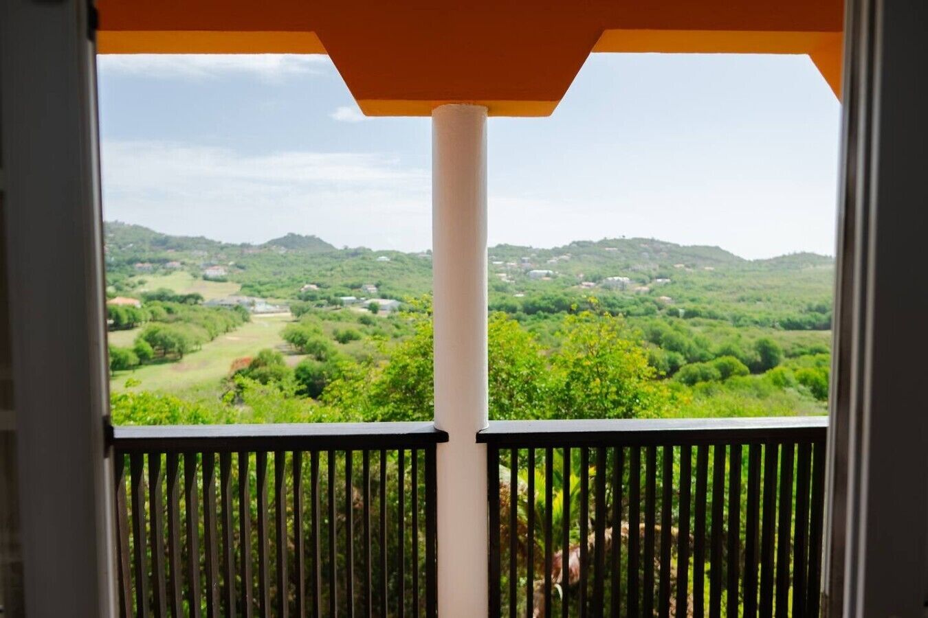 A balcony with a view of a green landscape and hills.