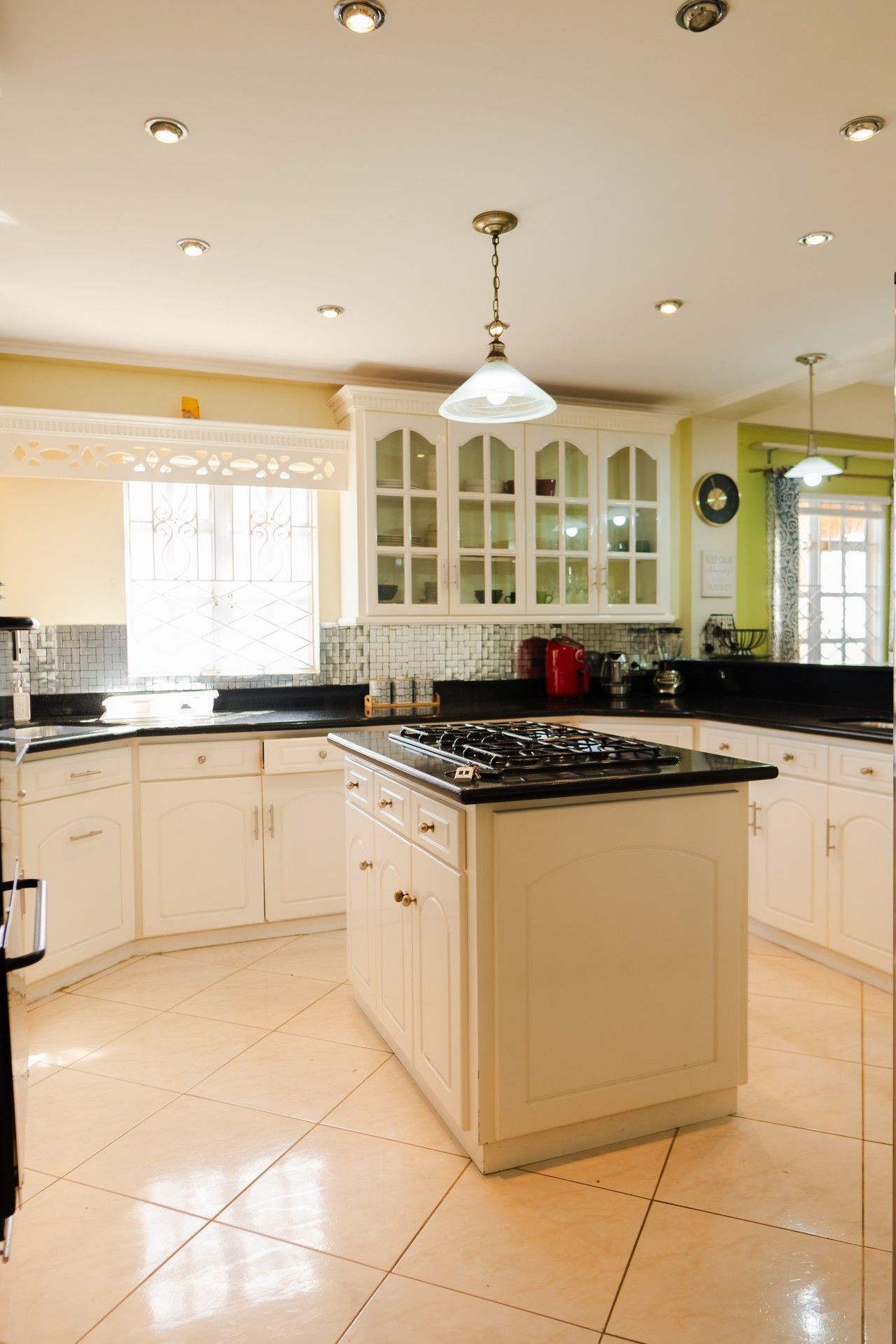 A kitchen with white cabinets, a central island with a stove, and a hanging light fixture.