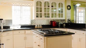 A kitchen with white cabinets, a central island with a stove, and a hanging light fixture.
