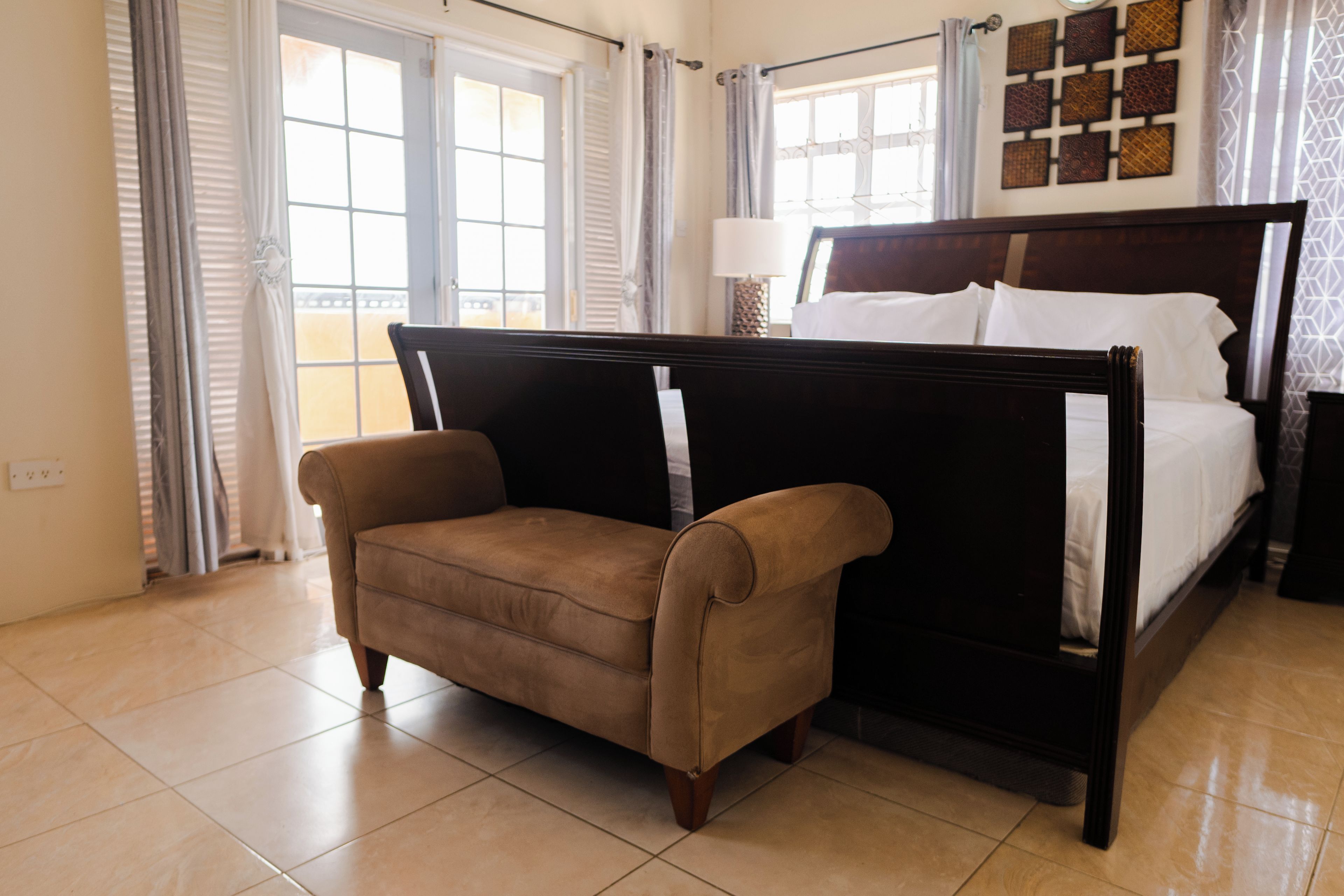 A bedroom with a bed, a chair, and a window with curtains.