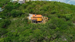 A hillside property with a single two-story building featuring a prominent orange roof and a balcony. - Cap Estate Private Caribbean Villa with Ocean Views (Gros Islet)