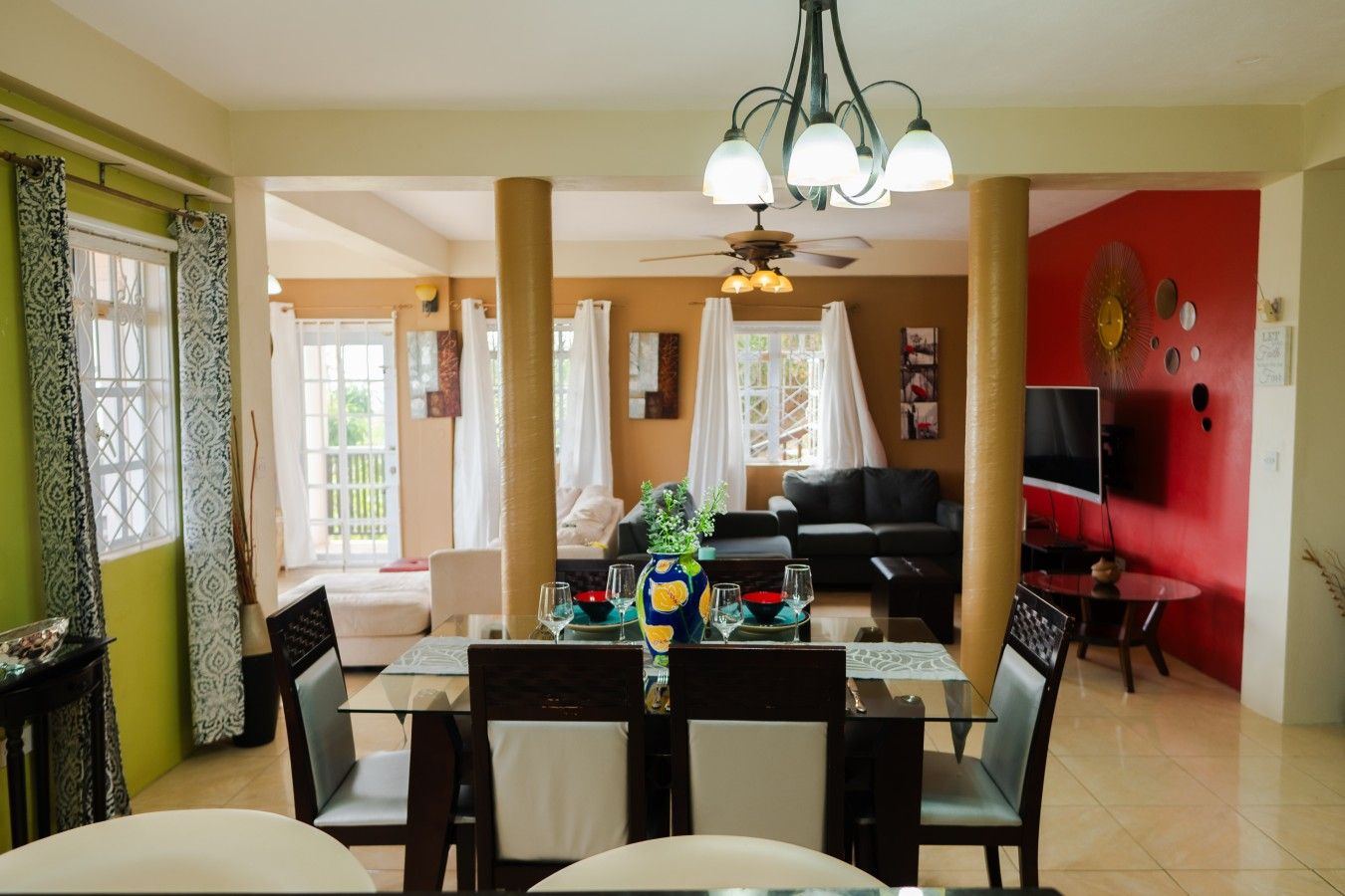 A dining area with a glass table, chairs, and a vase with flowers.