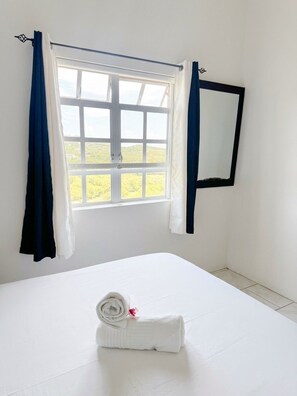 A room with a bed, a window with curtains, and a mirror on the wall. - Apartment in Cap Estate, Gros Islet (Gros Islet)
